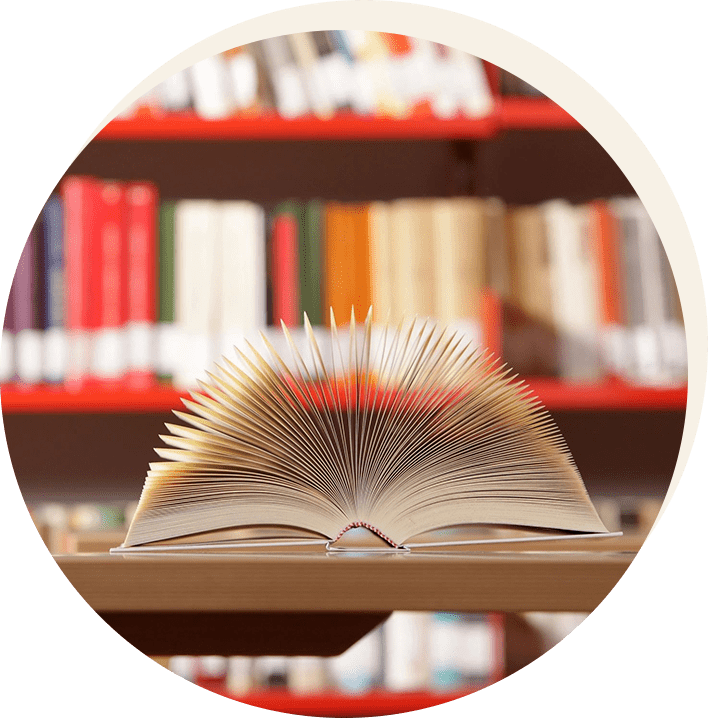 A book is open on the table in front of some books.