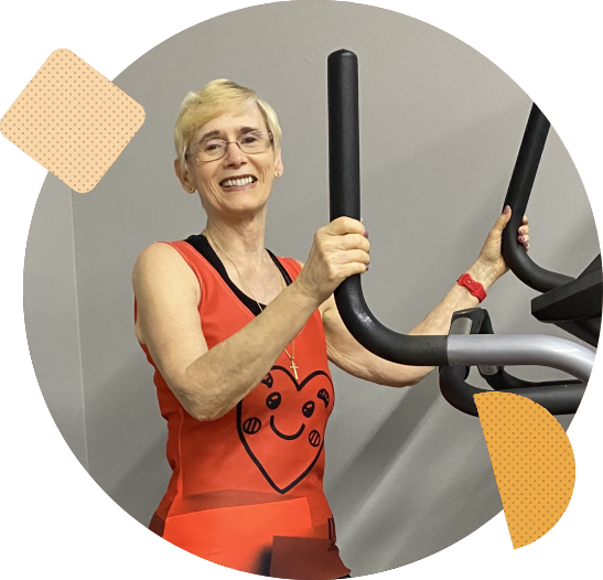 A woman is smiling while using an exercise bike.